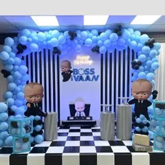 A 'Boss Baby' themed birthday party with a cool blue and black color scheme. The decoration includes character cutouts, a checkered floor design, and a custom neon sign for 'Boss Ivaan'.