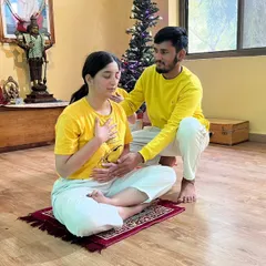 An instructor offers gentle guidance during a beginners' course, helping a student connect with their breath and body. Personal attention is key to building a strong and safe yoga foundation.