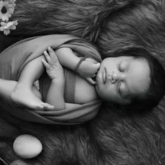 A classic black and white portrait emphasizes the beautiful, natural curl of a newborn. This pose is achieved safely and gently to capture how they were in the womb.