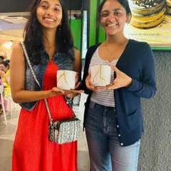 Two friends proudly hold up the matching Kintsugi-style mugs they decorated. It's a great way to create a beautiful set of usable art.