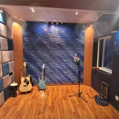 Another angle of our live room, highlighting the acoustic treatment and instrument setup. We have guitars available, and the wooden flooring adds to the warm acoustics of the space.