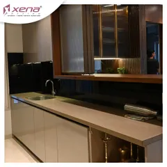 A closer look at the details of a neutral-toned kitchen. The combination of a light countertop, handle-less cabinets, and a dark, reflective backsplash creates a balanced and sophisticated look. I also integrated a bar and crockery unit for added functionality.