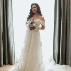 A beautiful bridal portrait, with the bride holding her bouquet and smiling, framed by soft window light.
