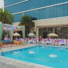 A beautiful poolside Haldi setup, combining colorful drapes with elegant seating. The floating umbrellas in the pool add a playful and unique touch to the celebration.