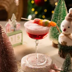 A whimsical Christmas cocktail garnished with candy. The festive props like the snowman and calendar set the scene perfectly.