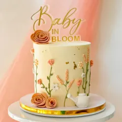 A sweet "Baby in Bloom" cake for a baby shower. This design features delicate, hand-piped wildflowers growing up the side of the cake, complete with a tiny watering can.