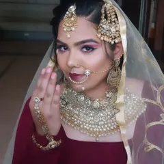 A traditional Muslim bridal look with a focus on heavy jewelry like the passa and nath. The eye makeup is bold with a winged liner to make a statement.