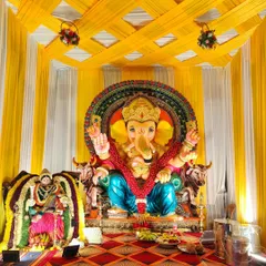 A close-up of the main stage for the Ganesh Chaturthi celebration. We used bright yellow and white striped fabric for the backdrop and ceiling, ensuring the focus remains on the beautifully adorned Ganesha idol.