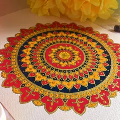 It’s always a bliss to have mandalas around you. This piece uses a warm, fiery palette of red, orange, and yellow, balanced with a deep blue. The gold accents make the colors truly sing.