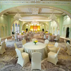 A grand ballroom set for a luncheon, featuring pastel green decor that complements the room's architecture. I ensure the dining setup is as beautiful as the ceremony itself.