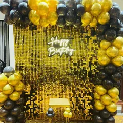 A classic and bold look with a gold shimmer wall framed by a black and gold balloon arch, perfect for any elegant birthday party.