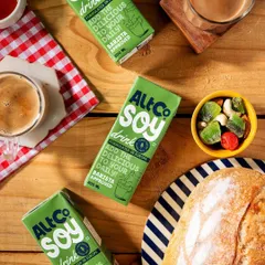 A cozy breakfast flatlay featuring Alt Co. Soy Drink. The overhead perspective, combined with a checkered napkin and fresh bread, creates a warm and inviting composition perfect for social media.