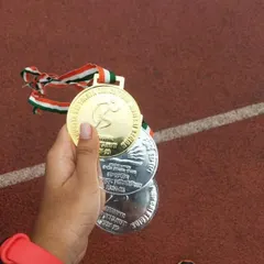 The reward for dedication. An athlete holds her gold and silver medals from the Kendriya Vidyalaya regional championship in the 100m, 200m, and Long Jump events.