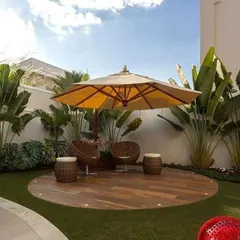 I created a dedicated relaxation zone in this large backyard using a circular wooden deck. Complemented by an oversized umbrella and comfortable wicker seating, it feels like a private island resort right at home.