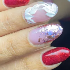 A close-up of a festive design with sparkling red nails and 3D white leaf accents.