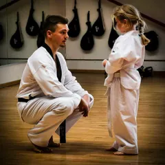 An instructor crouches down to speak with a young student. This shows our commitment to patient, one-on-one guidance for even our smallest members.