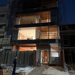 This shot shows the full front elevation of the modern Noida home, with its large windows and cantilevered balconies still surrounded by scaffolding.