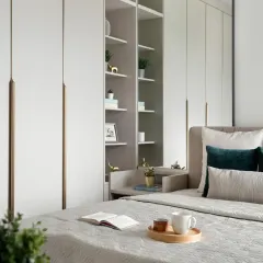 This view highlights the clever integration of a bedside unit within the wardrobe itself. The open, back-lit shelves provide a space for books and decor, replacing a traditional nightstand to save floor space.