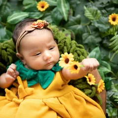 This one-month-old looks like a little sunflower herself. I used a cozy knit basket and a backdrop of lush leaves to create this nature-inspired newborn portrait, highlighting her delicate features.