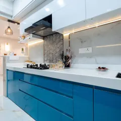A closer look at the high-gloss blue acrylic cabinets and the textured 3D tile backsplash. The under-cabinet LED lighting not only illuminates the workspace but also highlights the different textures in the design.