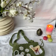 A beautifully styled shot of our green daisy book cover with a sling, shown with a matching small pouch and an AirPod case.