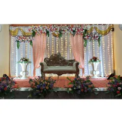 This is our classic reception stage design, featuring elegant peach and white drapery, a beautiful floral valance, and soft fairy lights. The ornate Diwan seating completes this timeless look for an indoor wedding hall.