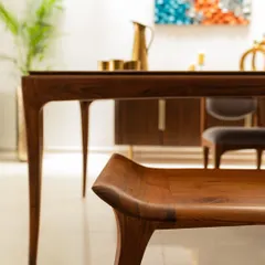 This dining set from Alankaram showcases exquisite craftsmanship. The elegantly curved legs of the bench and table are a beautiful example of contemporary Indian furniture design.