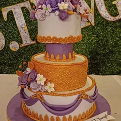 A grand, multi-tiered cake designed for a royal-themed celebration. The combination of purple and gold, intricate patterns, and floral arrangements creates a truly majestic and unforgettable centerpiece.