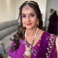 A regal look for a mature client. The purple smokey eye, combined with a traditional maang tikka and jewelry, creates a stunning and memorable appearance for a wedding.