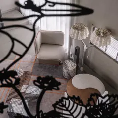 A creative perspective shot through the metal railing, looking down into the living area. The bird silhouette frames the scene below, adding a layer of artistic storytelling to the home's interior design.