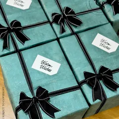 A close-up of our sophisticated teal and black gift wrapping. The high-quality textured paper and stitched grosgrain ribbon create a premium feel, suitable for discerning corporate clients or personal gifting.