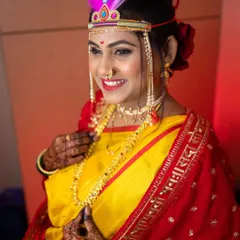 The pure joy of a bride on her wedding day. This look features a classic red and yellow nauvari, a traditional 'bashing' on her forehead, and glowing makeup for her Vidhi ceremony.