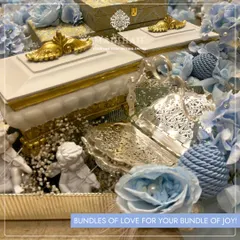 A beautiful arrangement for a baby boy, featuring a silver-plated filigree dish and a white keepsake box with gold trim. The hamper is surrounded by blue flowers, perfectly capturing 'Bundles of love for your bundle of joy'.