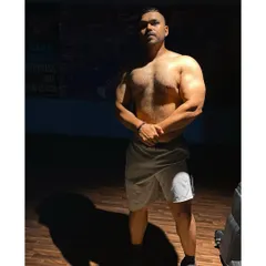 A physique shot in the gym. The dramatic lighting highlights the muscle and conditioning that I help my clients build.