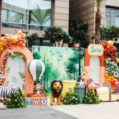 Sara's 'Wild Two' party was a vibrant jungle adventure. This full view shows the custom backdrop, life-sized animal props like a zebra and giraffe, a fun animal train, and colorful balloon arrangements.