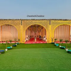 A wide-angle view of a royal wedding entrance. The yellow laser-cut panels create stunning archways, leading guests into the main event area over a lush green carpet.