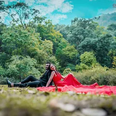 A wide-angle shot from a pre-wedding session in a lush green park. The dramatic red dress contrasts beautifully with the natural scenery, showcasing our ability to create visually stunning couple portraits.