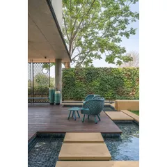 Stepping stones cross a tranquil water body that wraps around the deck, while a vertical garden wall adds another layer of green to this serene outdoor space.