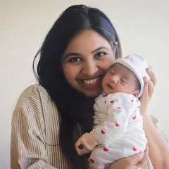 The beautiful, happy smile of a new mom holding her sleeping baby. These lifestyle hospital photos are relaxed and natural, capturing your joy in your own space.