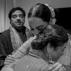 A bride shares a three-way hug with her parents just before walking to her groom. This black and white image beautifully captures the emotion and unity of the family in this significant moment.