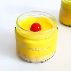 This is our Mango Charlotte, another seasonal favorite. It's a light and creamy dessert in a jar, with layers of cake and mango puree, topped with a cherry.