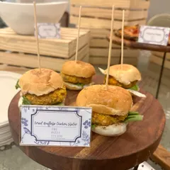 A close-up of our fried truffled chicken sliders. These bite-sized burgers are served on a wooden platter, each held together with a skewer, showcasing our attention to detail and gourmet flavor combinations.