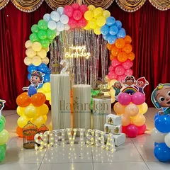A vibrant Cocomelon stage decoration with a rainbow balloon arch and a shiny fringe backdrop. I use multiple character cutouts and custom light-up letters to create a fun and personalized party scene.
