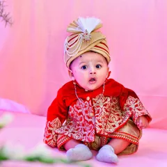 A vibrant, full-color portrait of a baby boy dressed in a traditional red and gold sherwani and turban. This shot highlights our ability to capture sharp, expressive images in themed setups.