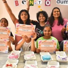 The proud graduates of our Bento Cake Kids Workshop! Each little chef is holding their certificate of completion and showing off the mini cake they baked and decorated all by themselves.