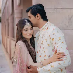 A sweet and gentle moment from a Mehendi ceremony, with the groom kissing the bride's forehead as they embrace.