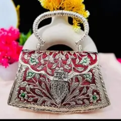 I love adding a touch of color to classic designs. This silver clutch features beautiful red and green enamel work, known as meenakari, making it a vibrant and unique statement piece.