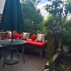 This little balcony has it all: a wooden deck, a bench with cushions, a dining table under an umbrella, a koi fish pond, and greenery all around. It's a sacred little abode for chilling.