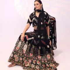 Seated gracefully, this view shows how the georgette fabric of the black lehenga drapes beautifully. The detailed floral embroidery at the hem provides a rich contrast to the modern chevron pattern on the rest of the outfit.