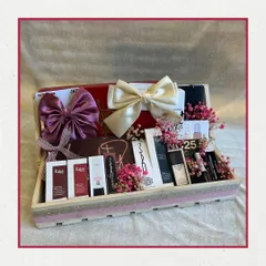 A sophisticated makeup hamper featuring products from K-Beauty brands and MAC. The items are elegantly displayed in a glitter-striped wooden tray, adorned with satin bows and dried flowers.
